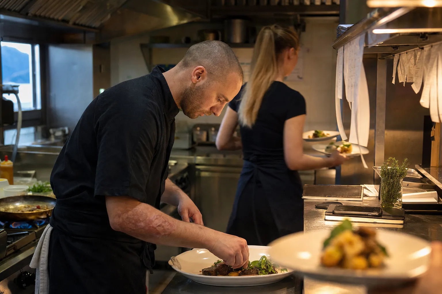 Chef dressant une assiette au passe d'une petite cuisine